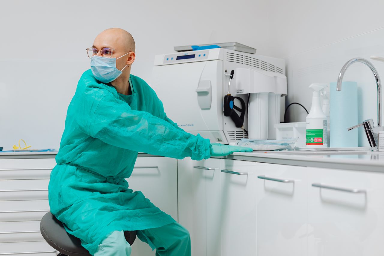 Dentist in PPE working in a modern, sterile clinic. Health and dental care focus.